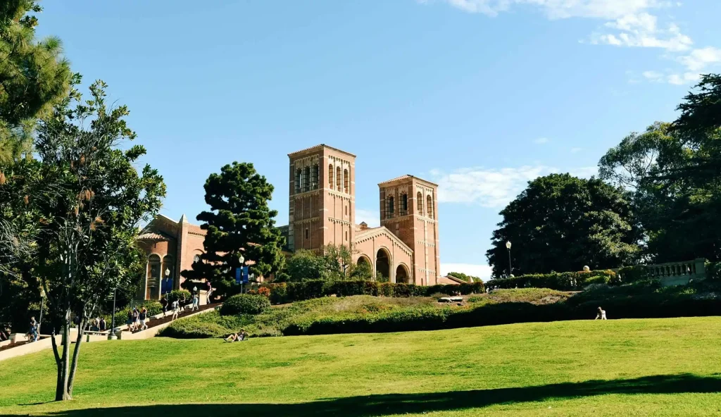 A scenic view of a university campus with iconic twin towers surrounded by greenery under a clear blue sky.