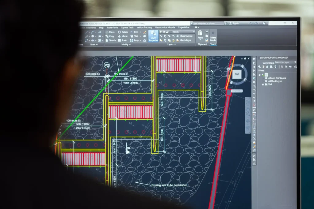 Engineer analyzing a technical blueprint on a computer screen using AutoCAD software.